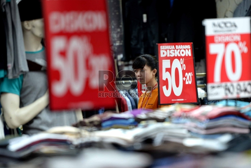 Penjaga menunggu pembeli di salah satu ritel penjualan pakaian di Pasar Baru, Jakarta Pusat, Senin (14/12).