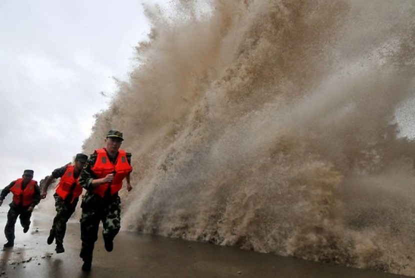 Penjaga pantai Cina berlari menghindari ombak. Topan Fitow menewaskan setidaknya lima orang di Cina
