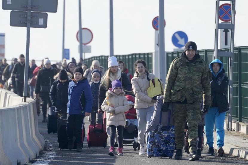 Penjaga perbatasan Polandia membantu pengungsi dari Ukraina saat mereka tiba di Polandia di perbatasan Korczowa, Polandia, Sabtu, 26 Februari 2022.