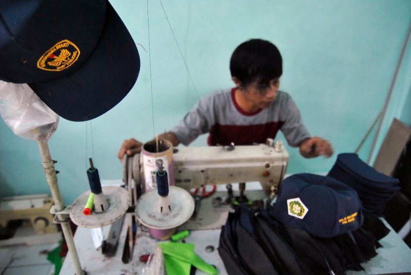 Penjahit mengerjakan pembuatan topi sekolah di industri rumahan. ilustrasi