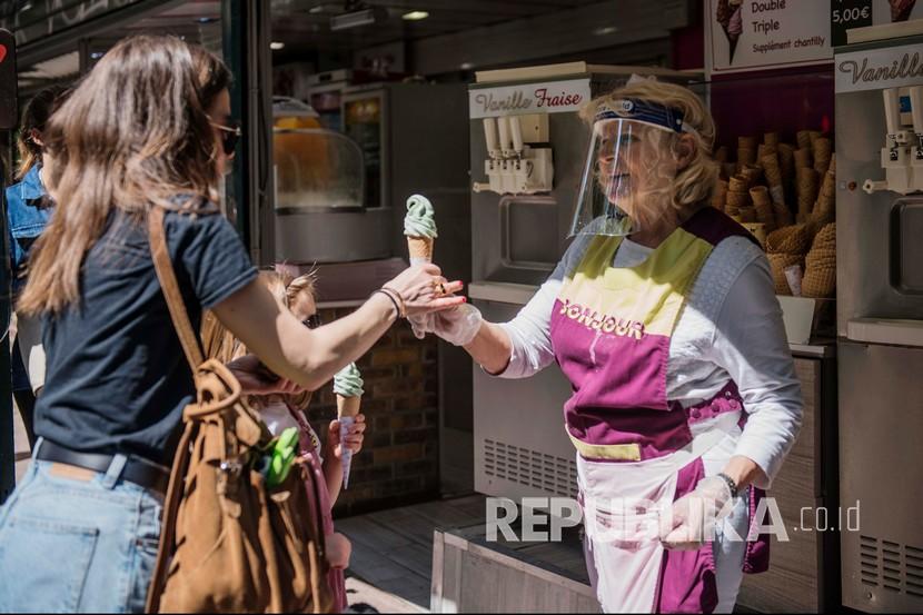  Penjual es krim dengan mengunakan masker bekerja pada akhir pekan pertama setelah dua bulan diberlakukannya lockdown di Paris, Prancis,Ahad (17/5). Prancis mulai melongarkan lockdown secara bertahap di tengah pandemi COVID-19. 