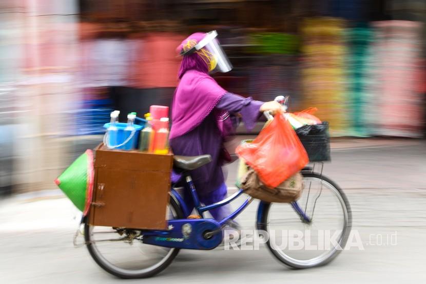 Penjual jamu keliling Tidar dengan menggunakan masker dan pelindung wajah menuntun sepeda di kawasan Pasar Baru, Jakarta, Selasa (9/6/2020). Tidar menerapkan protokol kesehatan jelang pemberlakuan protokol tatanan normal baru di Jakarta untuk tetap mencari nafkah. 