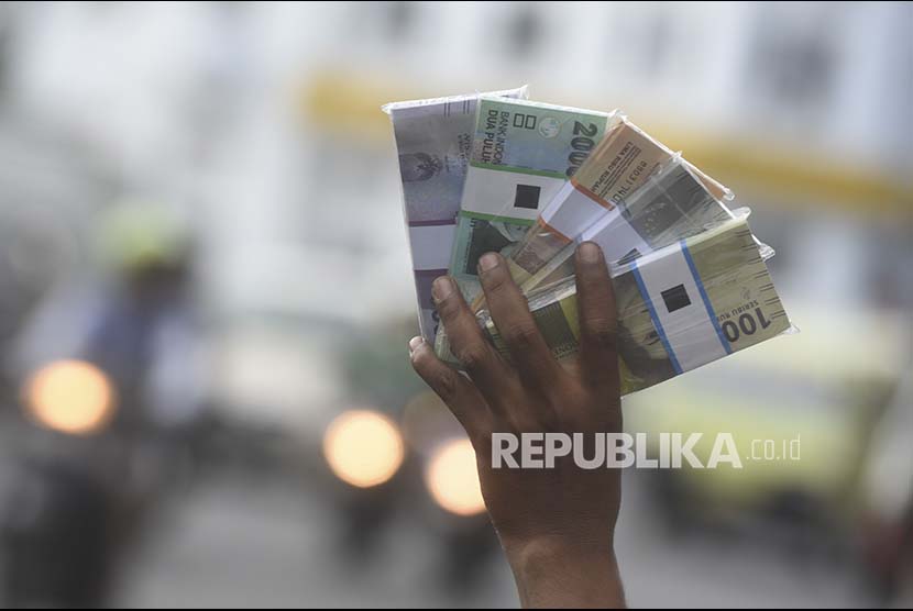 Penjual jasa penukaran uang baru menawarkan uang baru kepada pengguna jalan di pinggiran jalan, Surabaya, Jawa Timur, Selasa (6/6). Pada bulan Ramadan, para penjual jasa penukaran uang baru ramai bermunculan di pinggir-pinggir jalan, mereka menukarkan uang baru tersebut dengan tambahan 10 persen dari jumlah uang yang ditukarkan. 