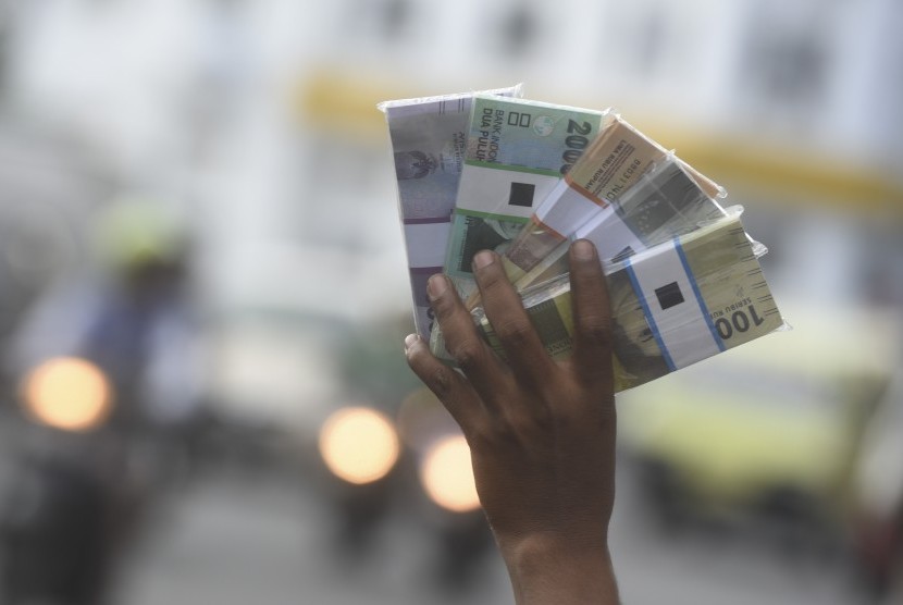 Penjual jasa penukaran uang baru menawarkan uang baru kepada pengguna jalan di pinggiran jalan, Surabaya, Jawa Timur, Selasa (6/6). Pada bulan Ramadan, para penjual jasa penukaran uang baru ramai bermunculan di pinggir-pinggir jalan.