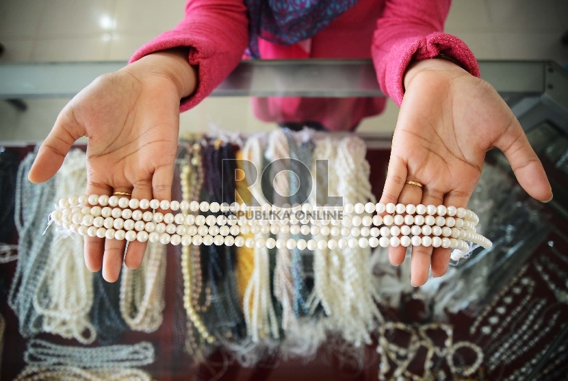 Penjual menunjukan perhiasan berupa mutiara air tawar yang dijual di sentra pusat perhiasan mutiara di Kawasan Sekarbela, Mataram, Nusa Tenggara Barat, Ahaad (21/12).