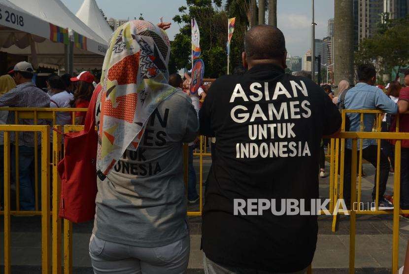 Penonton menggunakan baju Asian Games saat melakukan antre di gerbang tiket opening ceremony Asian Games 2018, di kompleks Gelora Bung Karno Jakarta, Sabtu (18/8). 