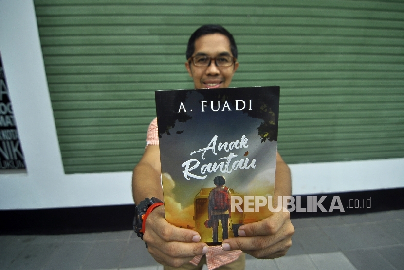 Penulis novel Ahmad Fuadi berfoto sekaligus memperlihatkan novelnya disela-sela saat wawancara di Kantor Republika, Jalan Warung Buncit, Jakarta, Selasa (5/9). 