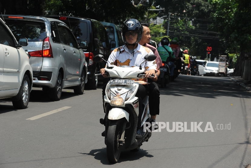 Penumpang angkutan ojek online tidak menggunakan Helm di daerah Jalan Rawajati Barat, Jakarta, Rabu (22/09).