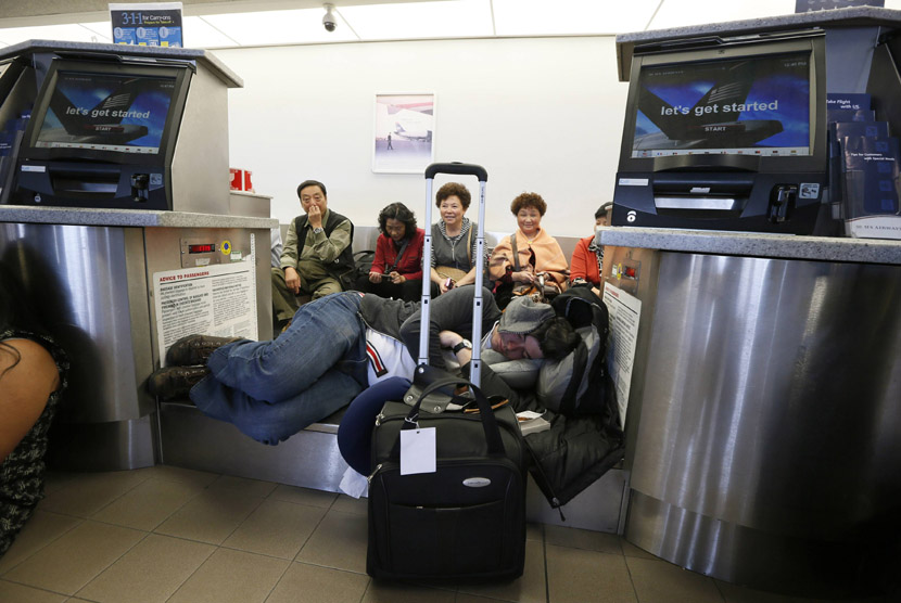  Penumpang beristirahat di area pengambilan bagasi setelah penerbangan mereka tertunda akibat insiden penembakan di Bandara Los Angeles (LAX), California,Jumat (1/11) waktu setempat.  (REUTERS/Lucy Nicholson)