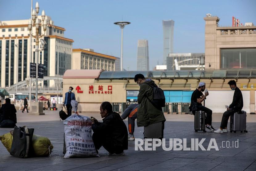 Penumpang dengan mengenakan masker menunggu di luar stasiun kereta api Beijing, Cina, Senin (13/4). Cina meningkatkan pengawasan terhadap masuknya orang asing serta memperketat pengaturan perbatasan setelah kasus COVID-19 impor mencapai rekor beberapa hari terakhir. 