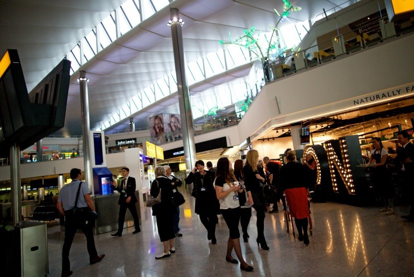 Penumpang melewati sederetan toko dan restoran di Bandara Heathrow, Inggris. Lonjakan penumpang di musim panas membuat para petugas Bandara Heathrow kewalahan. Ilustrasi.