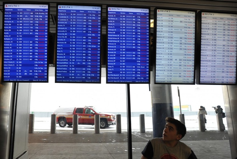 Penumpang melihat jadwal penerbangan di Bandara LaGuardia, New York.