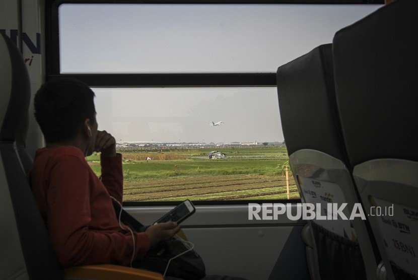 Penumpang melihat pesawat terbang dari dalam kereta bandara Railink di Tangerang, Senin (15/10). 