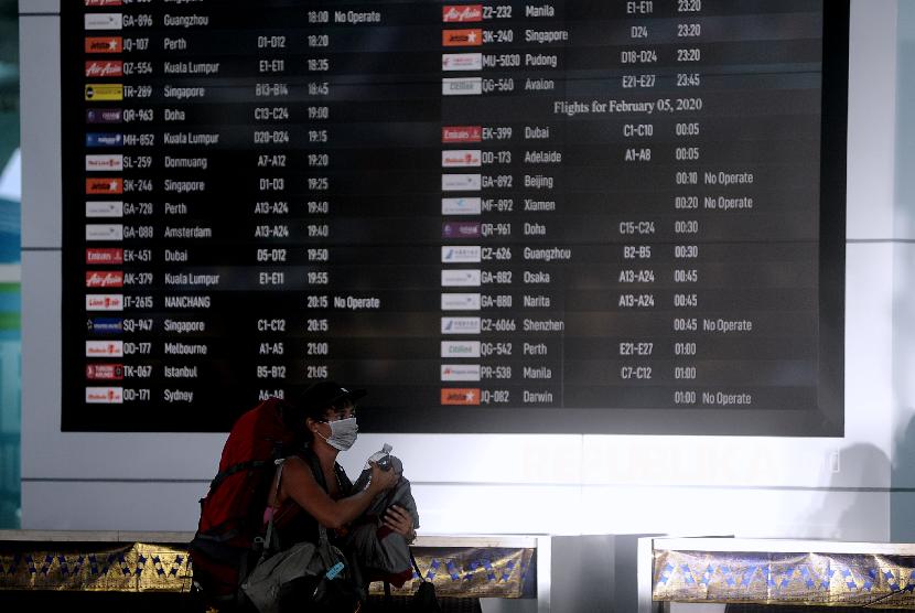Penumpang melintas di dekat layar informasi penerbangan di Terminal Keberangkatan Internasional Bandara Internasional I Gusti Ngurah Rai, Bali, Selasa (4/2/2020). Pemerintah melalui Kementerian Perhubungan memutuskan penundaan penerbangan dari dan menuju seluruh destinasi di 