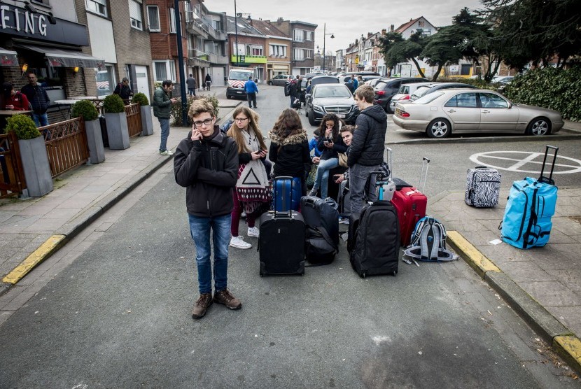 Penumpang menunggu dengan barang-barang mereka dekat bandara Brussels di Zaventem, Belgia, (22/3). Puluhan orang tewas dan terluka dalam ledakan ganda di ruang keberangkatan dari Bandara Zaventem di Brussels.