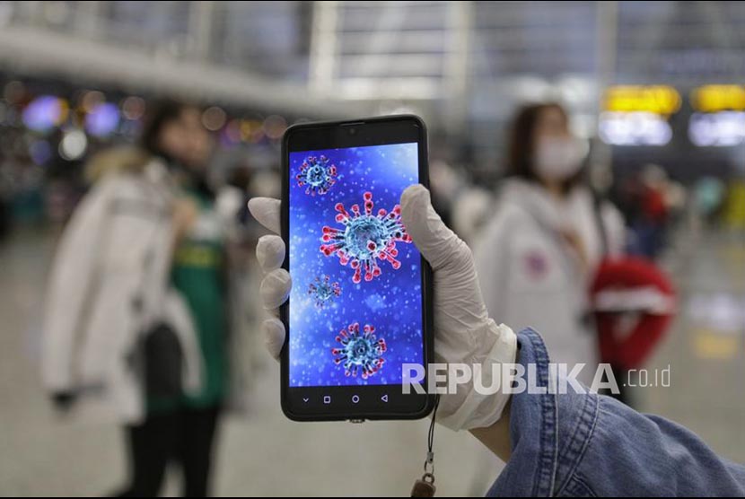 Penumpang menunjukkan gambar ilustrasi coronavirus pada ponselnya di  Bandara Guangzhou, Provinsi Guangdong, China.