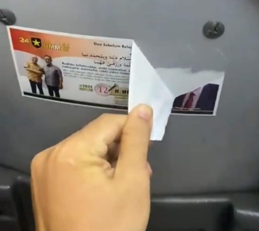 Penumpang menyobek stiker caleg Partai Ummat di bus Transjakarta.