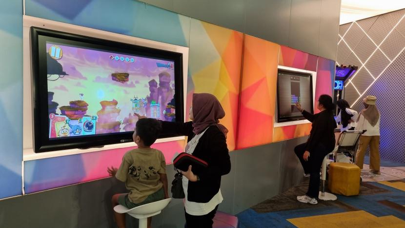 Penumpang pesawat menikmati fasilitas permainan digital di Bandara Soekarno-Hatta yang dikelola oleh Angkasa Pura II.