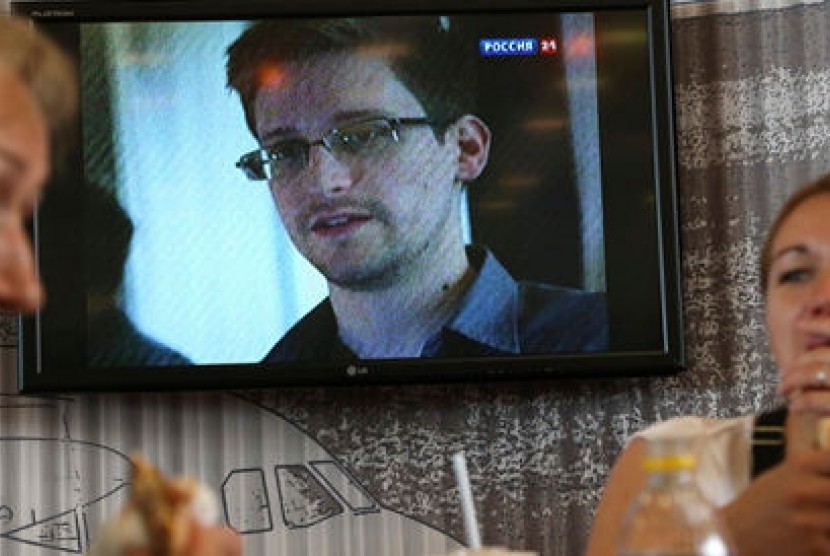 Penumpang tengah bersantap di sebuah cafe di Bandara Transit Sheremetyevo Moskow, dengan layar televisi yang menayangkan berita tentang Edward Snowden.