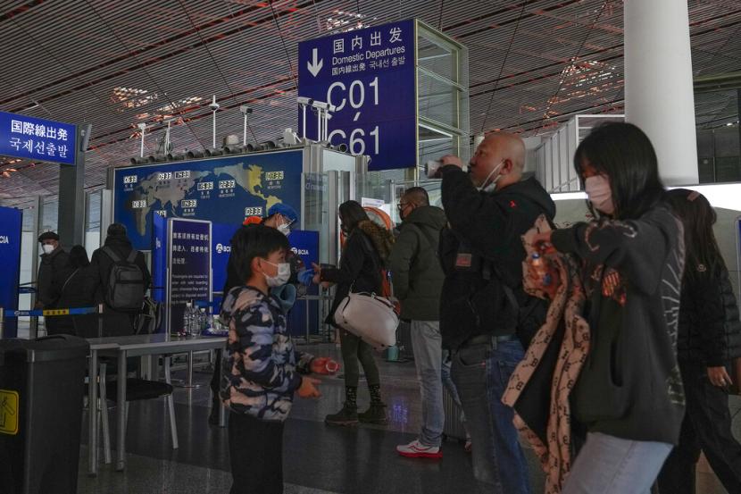 Penumpang yang memakai masker berbaris untuk pemeriksaan keamanan untuk memasuki gerbang keberangkatan internasional di Bandara Internasional Ibukota Beijing, Beijing, China.