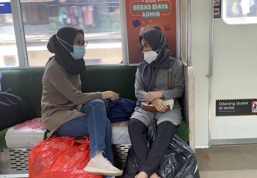 Penumpang yang mengenakan masker pelindung duduk di dalam kereta yang meninggalkan stasiun kereta api di Jakarta, Indonesia, Kamis, 16 Desember 2021. 