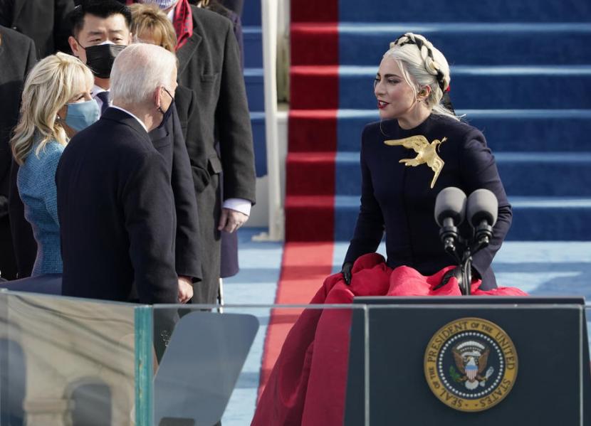 Penyanyi Lady Gaga menyapa Presiden AS Joe Biden usai menyanyikan lagu kebangsaan dalam rangkaian acara pelantikan presiden AS ke-46, Capitol, Washington, AS, Rabu (20/1) waktu setempat. Gaga tampak mengenakan bros besar berbentuk merpati.