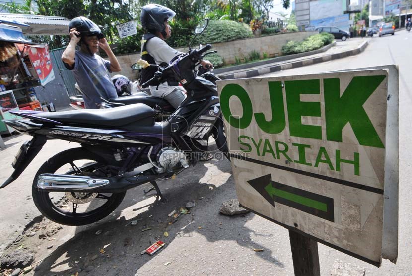  Penyedia jasa  angkutan sepeda motor (ojek) melayani penumpang di pangkalan Ojek Syariah, Jalan KH Abdullah Syafi'ie, Tebet Barat, Jakarta, Selasa (7/1).   (Republika/Aditya Pradana Putra)
