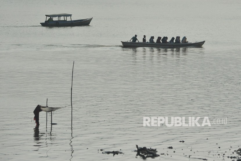 Penyedia jasa penyeberangan perahu membawa penumpang melintasi Sungai Batanghari yang diselimuti kabut asap tipis di Jambi, Rabu (14/8/2019). 