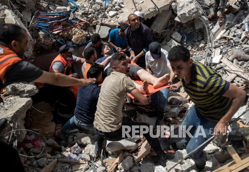  Penyelamatan warga Palestina yang selamat dari bawah reruntuhan bangunan tempat tinggal yang hancur setelah serangan udara Israel yang mematikan di Kota Gaza, Ahad (16/5).