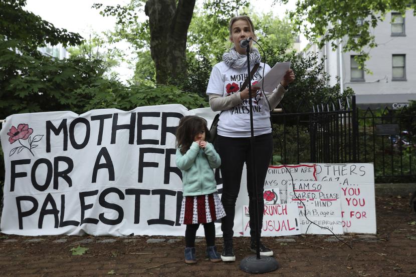 Penyelenggara Helena Pylvainen berbicara ketika putrinya, Lumi Moor, berdiri di sisinya saat sekelompok ibu berkumpul untuk memprotes perang di Gaza pada Hari Ibu di Philadelphia, Ahad, 12 Mei 2024. 