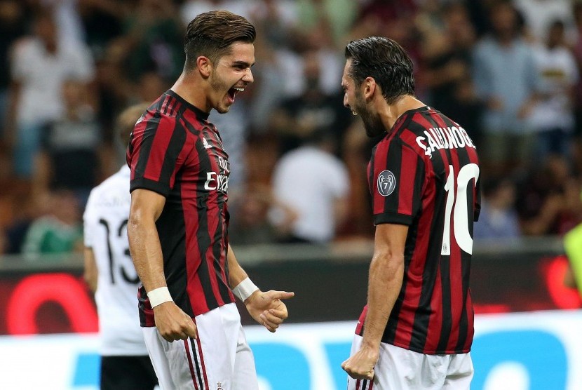 Penyerang AC Milan, Andre Silva (kiri, merayakan kemenangan atas Shkendija bersama rekan setimnya, Hakan Hakan Calhanoglu pada leg pertama playoff Liga Europa di Stadion San Siro, Jumat (18/8) dini hari WIB. 