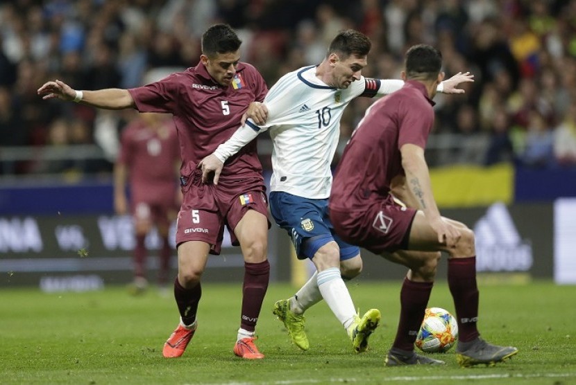 Penyerang Argentina Lionel Messi (tengah) diapit dua pemain Venezuela.