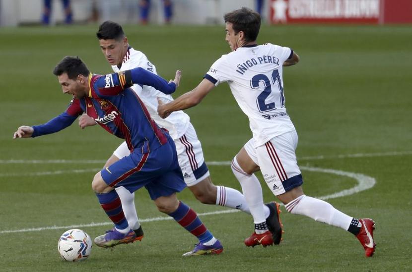 Jalannya pertandingan Barcelona vs Osasuna, Ahad (30/11). Dalam foto, penyerang Barcelona Lionel Messi (kiri) dijaga dua pemain Osasuna.