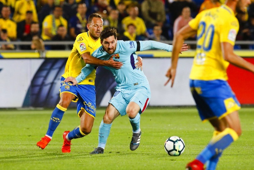 Penyerang Barcelona Lionel Messi (tengah) ditahan pemain Las Palmas Dani Castellano dalam laga pekan ke-26 La Liga di Stadion Gran Canaria, Pulau Canary, Las Palmas, Jumat (2/3). Barcelona ditahan imbang 1-1.
