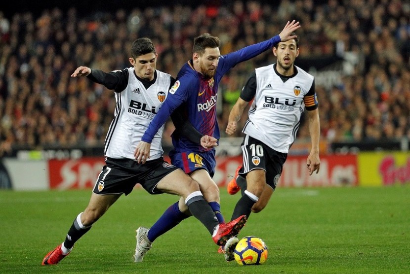 Penyerang Barcelona, Lionel Messi (tengah) saat melewati pemain Valencia.