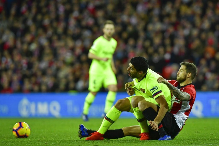 Penyerang Barcelona Luis Suarez (kedua kanan) terjatuh saat berduel bola dengan pemain Athletic Bilbao Inigo Martinez.