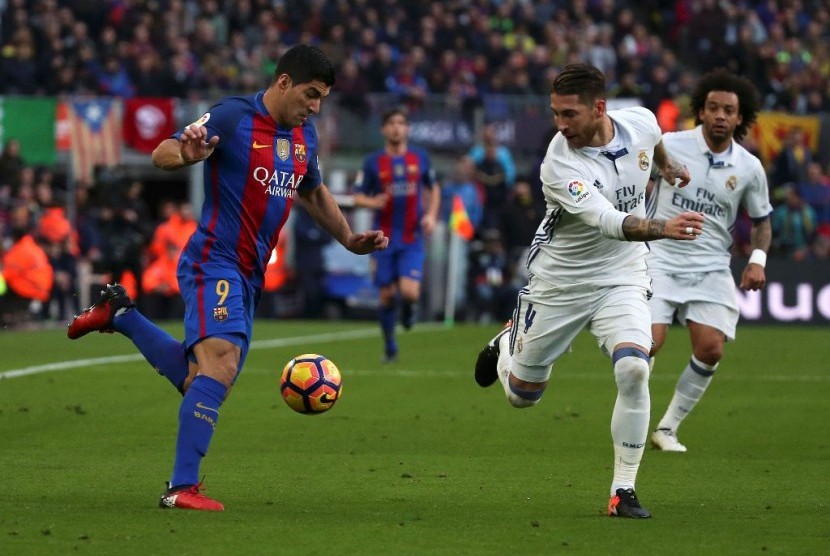 Penyerang Barcelona Luis Suarez kiri dibayangi oleh bek Real Madrid Sergio Ramos. Keduanya mencetak gol dalam pertandingan yang berakhir imbang 1-1.
