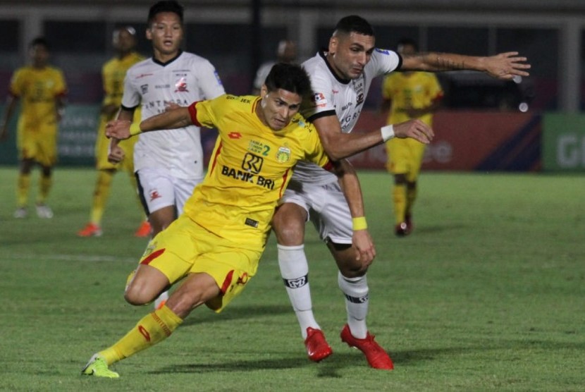 Penyerang Bhayangkara FC Ramiro Fergonzi (kuning) berebut bola dengan bek Madura United Jaimerson Silva.