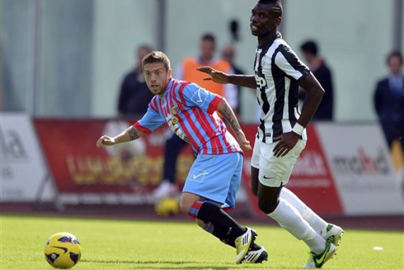 Penyerang Catania, Alejandro Gomez, terlihat berebut bola dengan gelandang Juventus, Paul Pogba, pada partai yang berlangsung di Stadio Angelo Massimino, Catania, Ahad (28/10) malam.