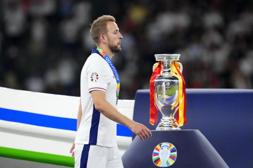 Penyerang Inggris Harry Kane melewati trofi Euro 2024. Kane gagal juara, tapi pulang dengan gelar top skor Euro 2024 dengan tiga gol.