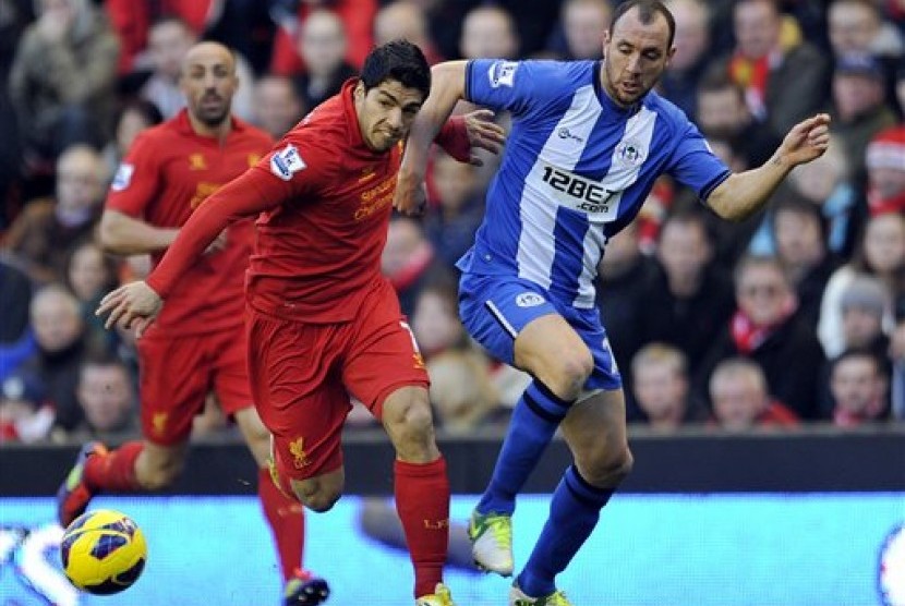 Penyerang Liverpool, Luis Suarez, saat berduel dengan bek Wigan, Ivan Ramis, di Anfield Stadium, Sabtu (17/11). Laga itu berkesudahan 3-0 untuk The Reds.