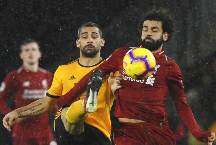 Penyerang Liverpool Mohamed Salah berusaha melindungi bola dari rebutan pemain Wolverhampton Wanderers.