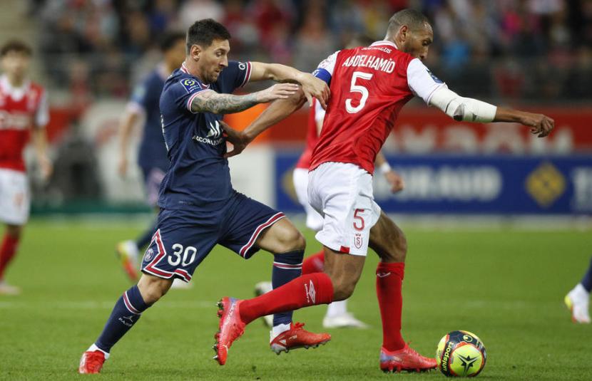 Penyerang Paris Saint-Germain Lionel Messi (kiri) berebut bola dengan pemain Reims Yunis Abdelhamid dalam pertandingan Ligue 1 Prancis, Senin (30/8) dini hari WIB.i
