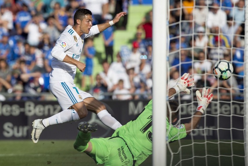 Cristiano Ronaldo (kiri) menaklukan kiper Getafe Vicente Guaita pada laga La Liga Spanyol pada lanjutan La Liga Spanyol di Stadion Coliseum Alfonso Perez, Sabtu (14/10) waktu setempat.