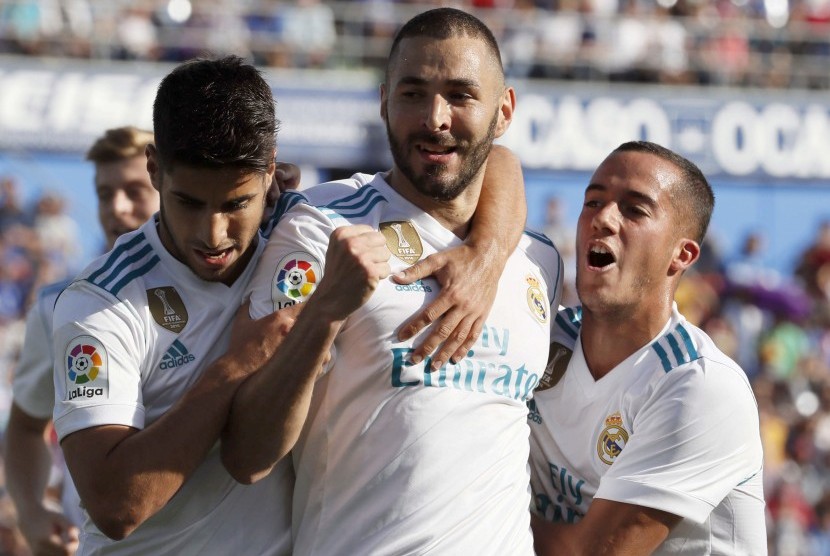 Penyerang Real Madrid asal Prancis Karim Benzema (tengah) merayakan golnya ke gawang Getafe bersama rekan setimnya, Marco Asensio (kiri) dan Lucas Vazquez pada lanjutan La Liga Spanyol di Stadion Coliseum Alfonso Perez, Sabtu (14/10) waktu setempat. 