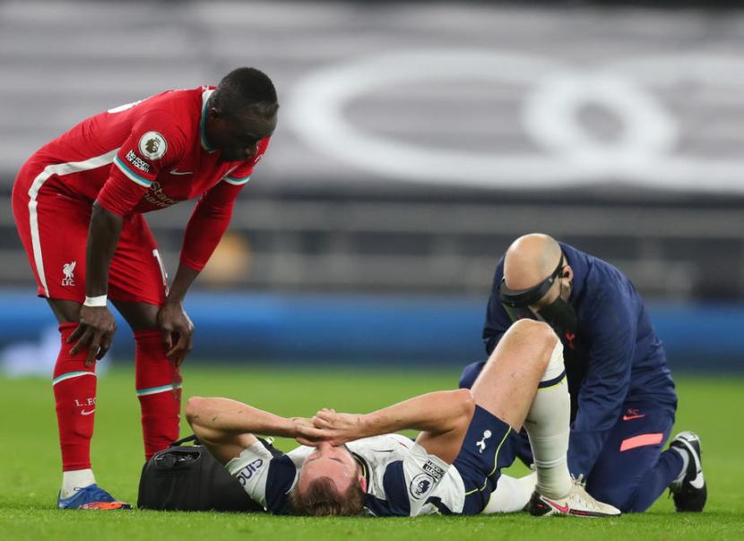 Penyerang Tottenham Hotspur Harry Kane (berbaring) mendapatkan perawatan dalam pertandingan melawan Liverpool