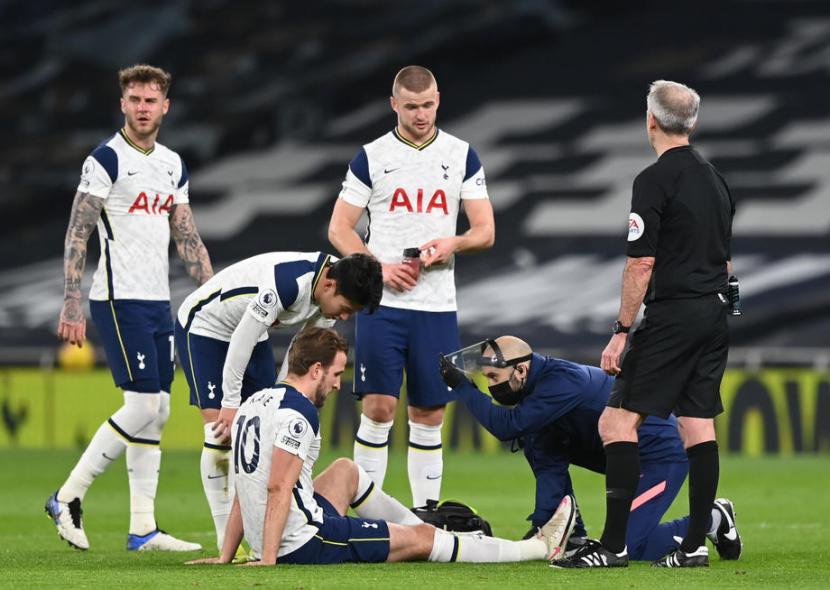 Penyerang Tottenham Hotspur Harry Kane (duduk) menerima perawatan di tengah laga kontra Liverpool. Kane mengalami cedera engkel.