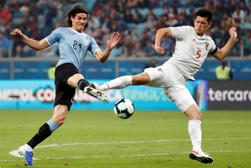 Penyerang Uruguay Edinson Cavani (kiri) dijaga bek Jepang Naomichi Ueda.