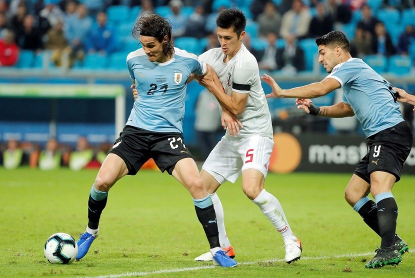 Penyerang Uruguay Edinson Cavani (kiri) dijaga pemain Jepang pada laga Copa America 2019.