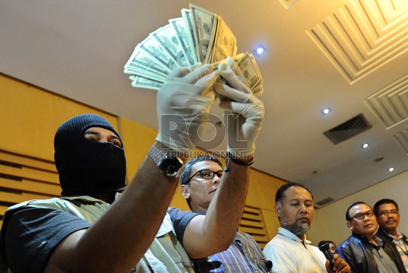  Penyidik KPK menunjukan uang dolar saat gelar barang bukti dalam operasi tangkap tangan di kantor KPK, Jakarta, Ahad (15/12).